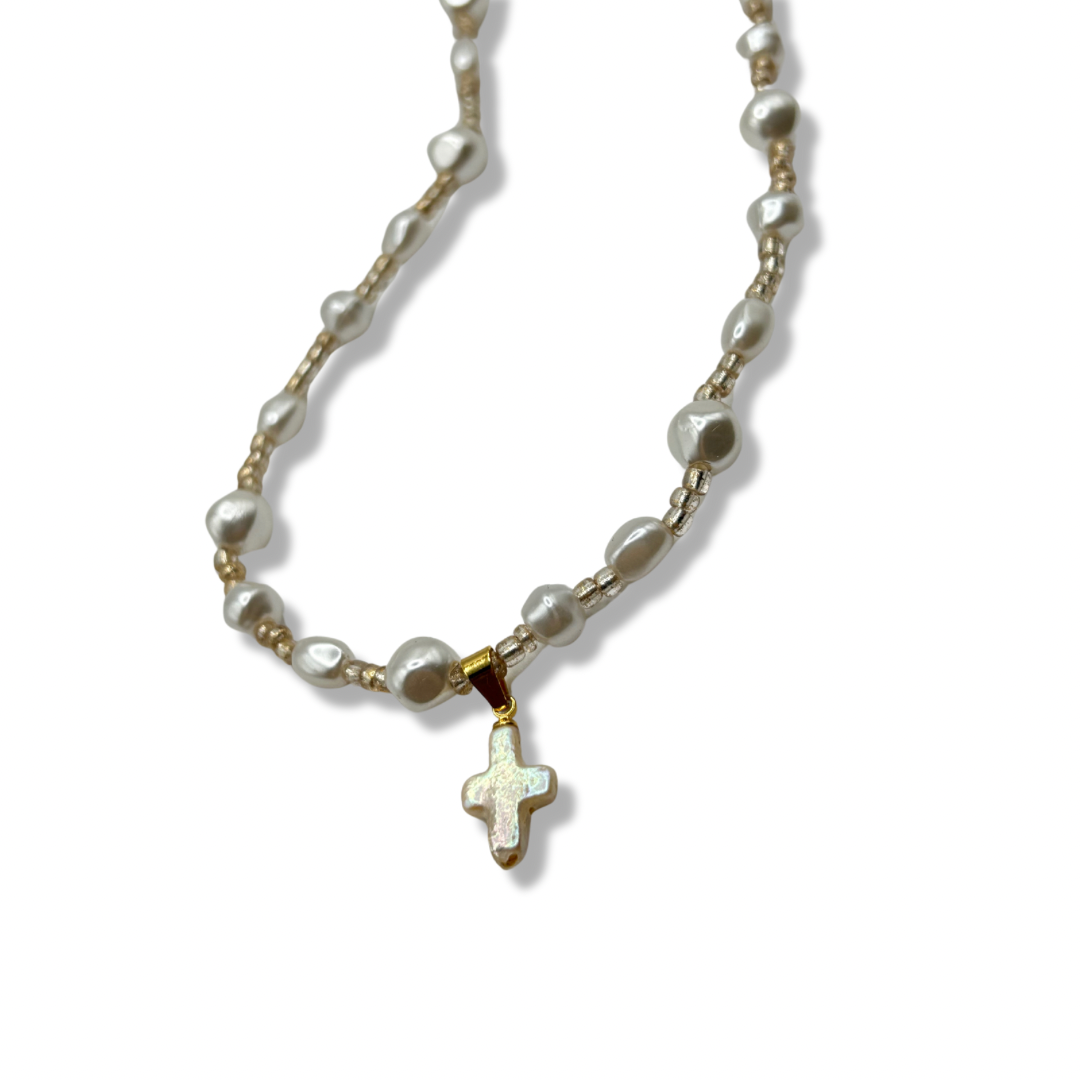 a close up of a freshwater pearl gold rosary necklace with a pearl cross pendant