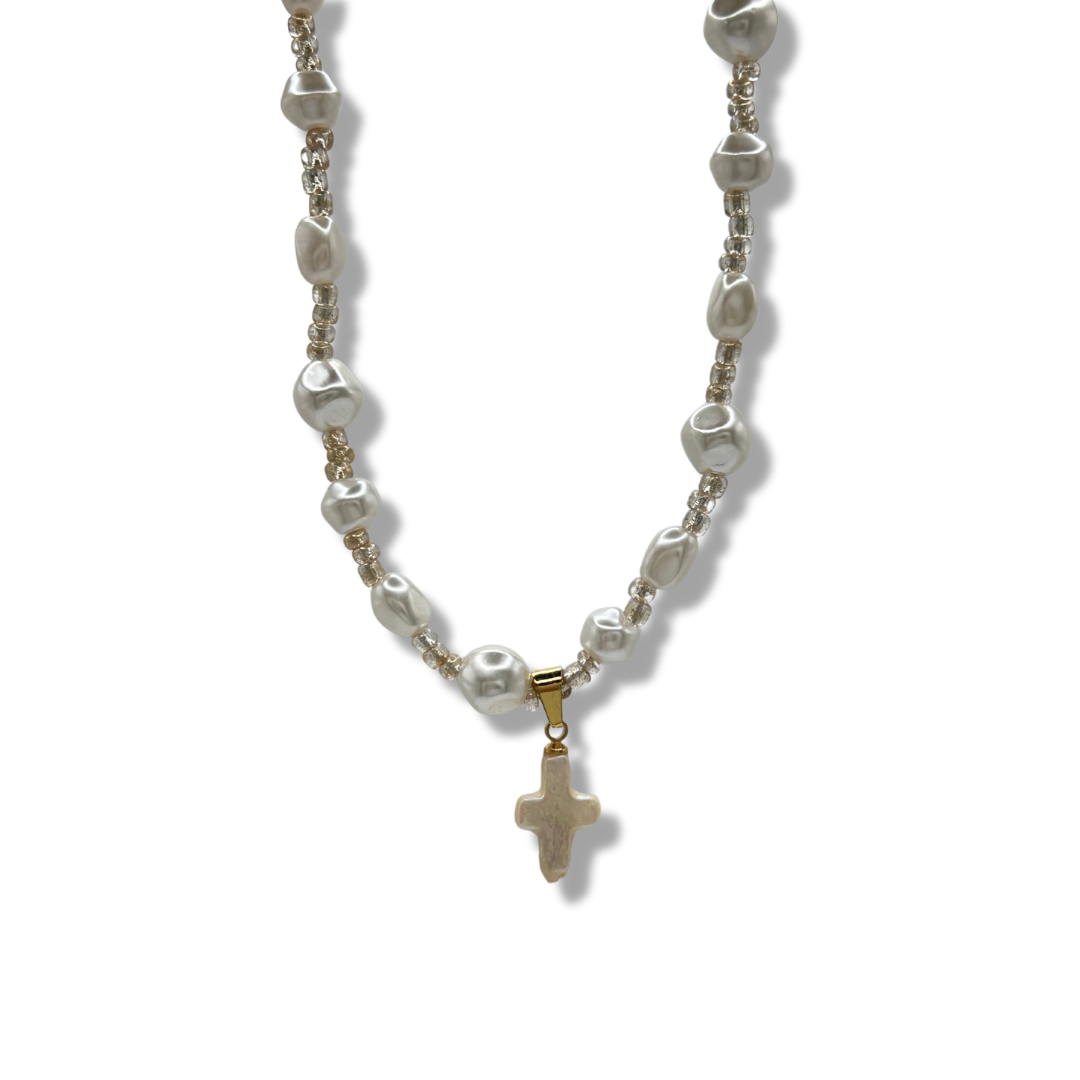 an up close shot of a freshwater pearl gold rosary necklace with a pearl cross pendant