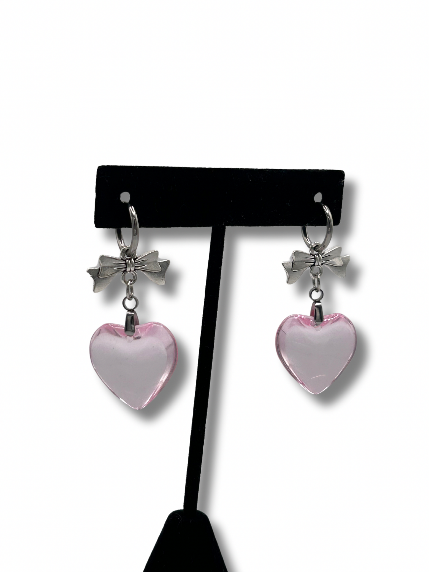 2 earrings featuring clear pink love heart pendants hanging off a silver bow