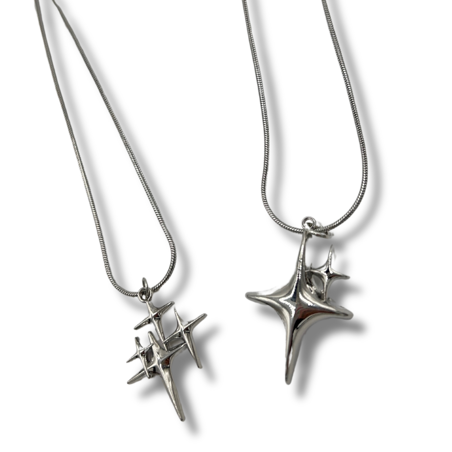 2 silver necklaces that look like stars shining, 1 is smaller with more sparkles, and the other is a larger star