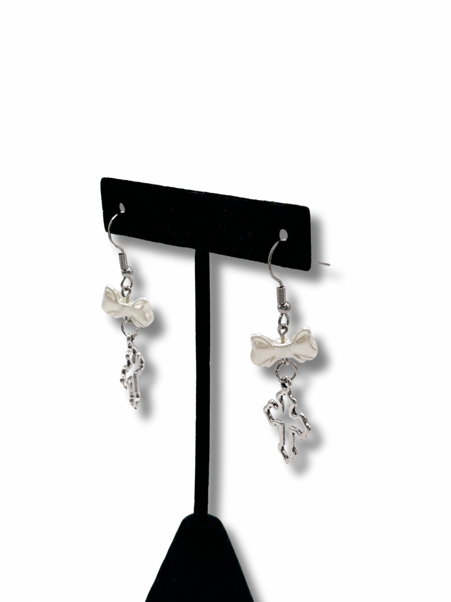2 earrings featuring white pearl bows with a hanging silver cross under them