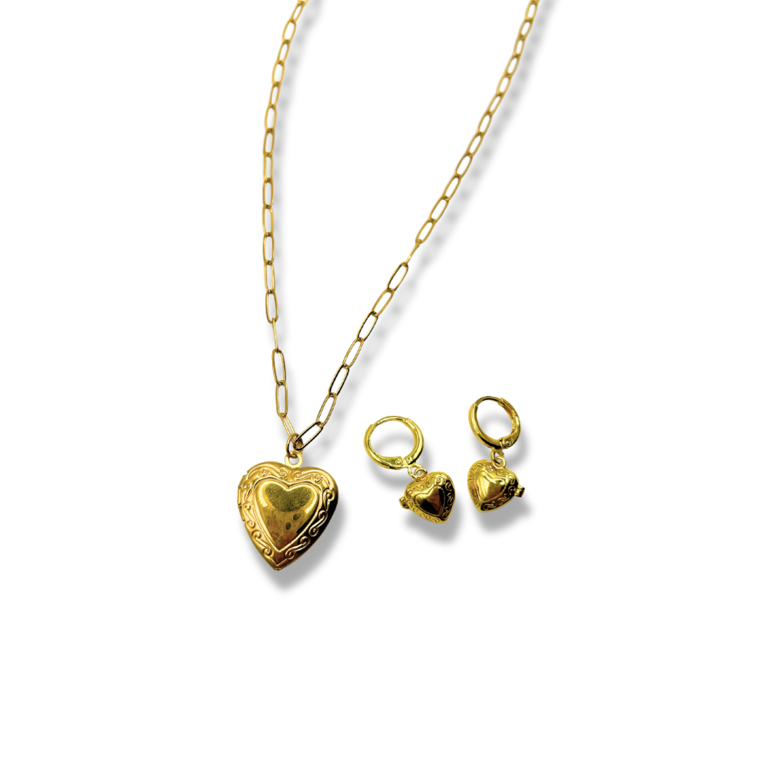 a dainty gold chain with a detailed heart shaped locket pendant. next to a matching pair of gold heart locket earrings