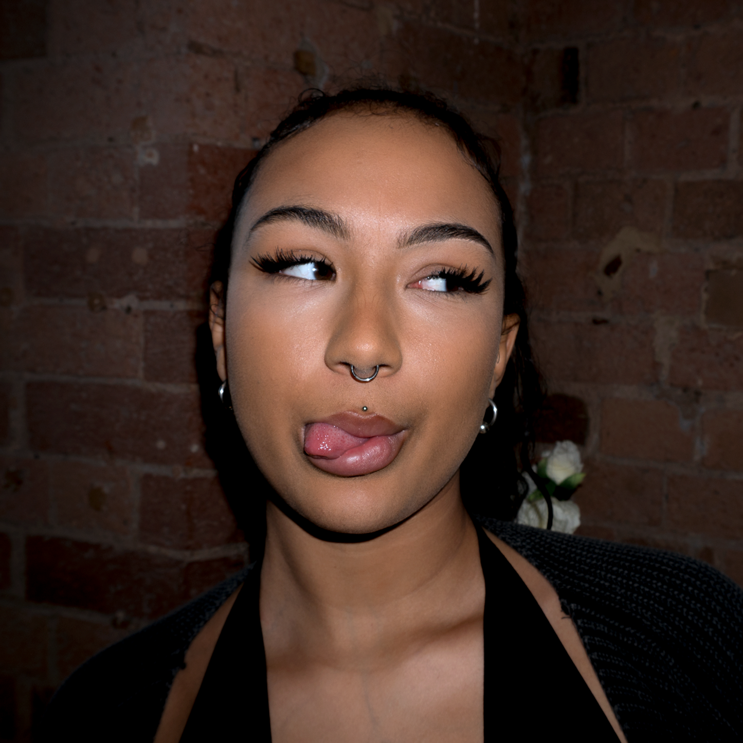 Close up of a models face sticking her tongue out and wearing silver hoop earrings