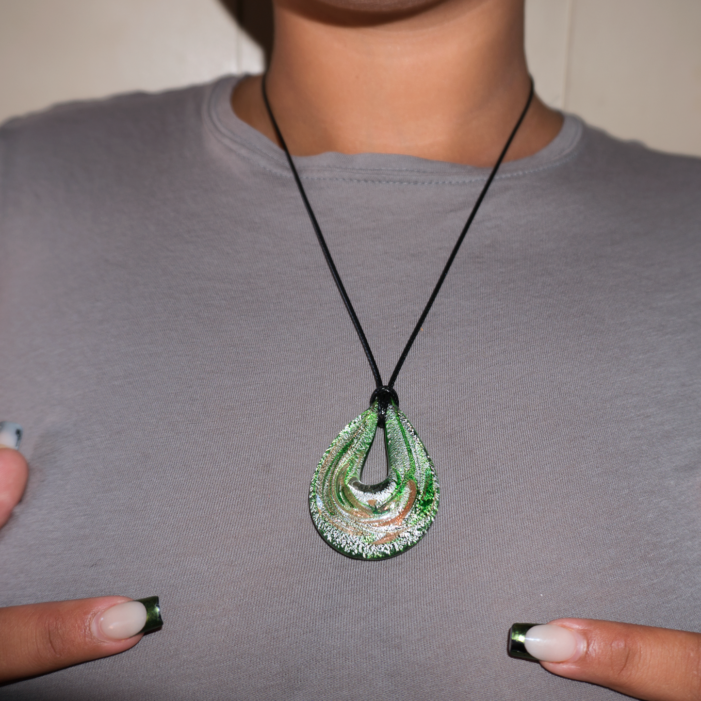 Close up of green blown glass tear drop style necklace worn by a model