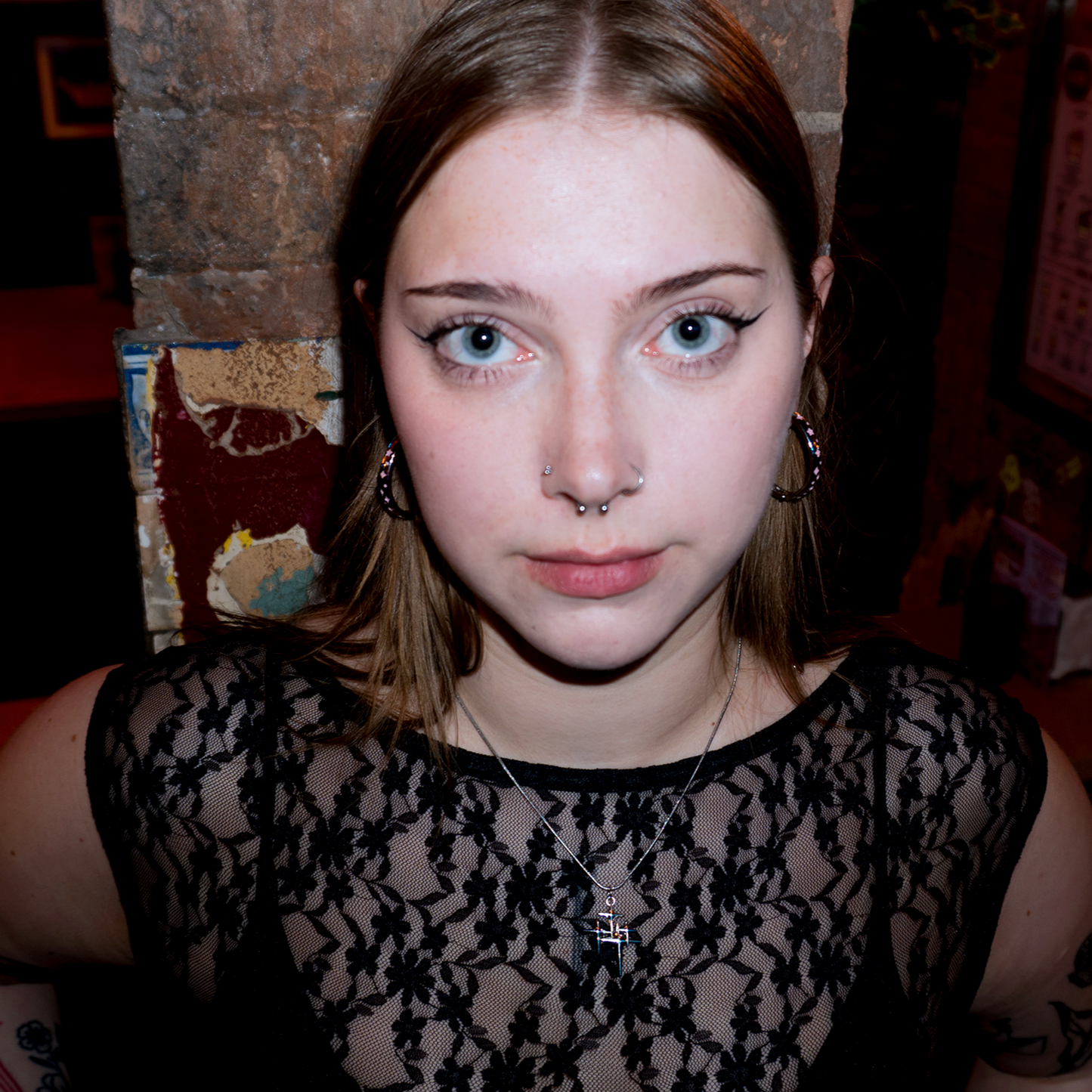 Close up shot of models face wearing the stargirl necklace, paired with hooped silver earrings with small pink sparkles in the details