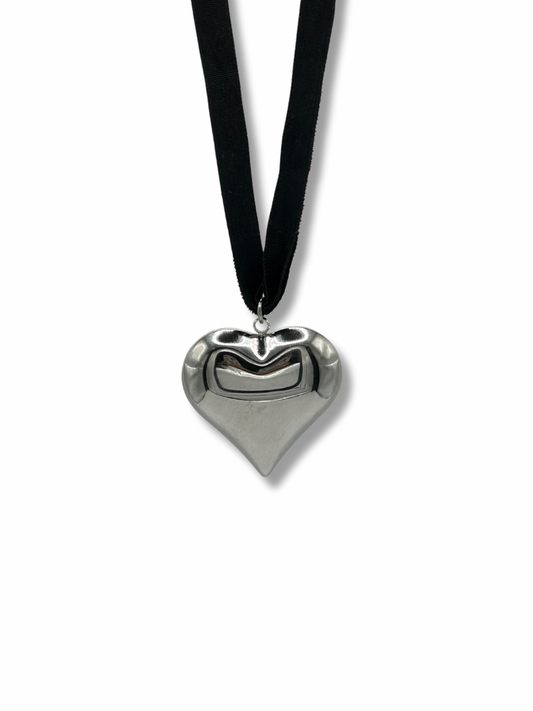 Silver heart pendant hanging on a black ribbon necklace